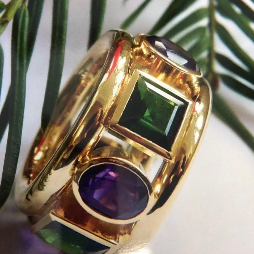 Breiter Gelbgoldring mit grünem Carré-Stein und violettem Cabochon