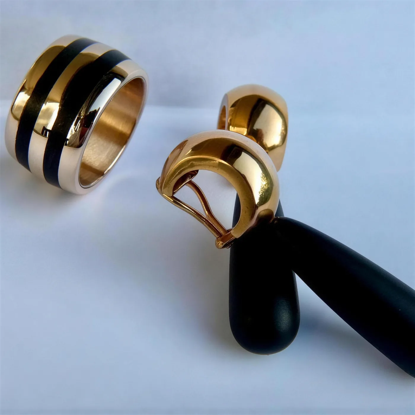 Breiter Goldring mit schwarzen Einlagen, dazu goldene Ohrclips mit schwarzen Tropfen